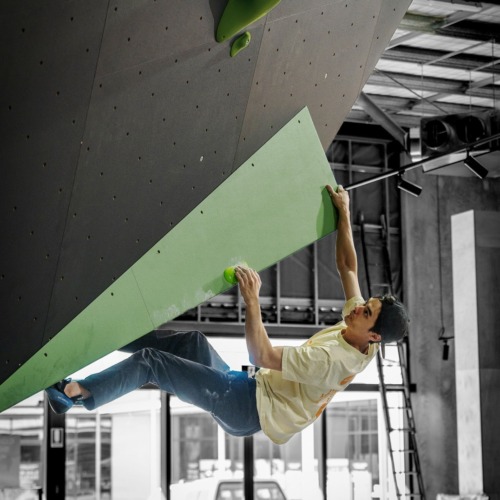Climber pulling on a green Gus.G1.2.L ICP Volume mounted to a climbing wall