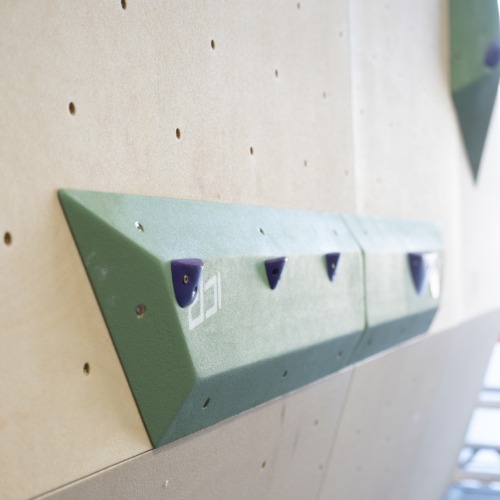 Medium green ICP Harry H2.6-7 M thin rail climbing volume on a wood-textured wall, fitted with small jib footholds for precision footwork.