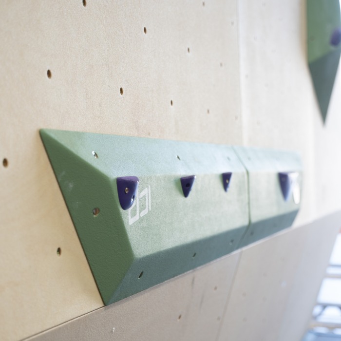 Medium green ICP Harry H2.6-7 M thin rail climbing volume on a wood-textured wall, fitted with small jib footholds for precision footwork.