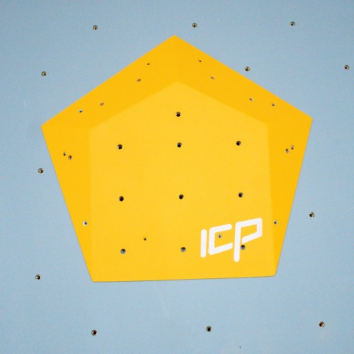 Small yellow ICP Ivy I2.2 S climbing volume with multiple t-nuts, fixed to a grey textured climbing wall for versatile hold placement.