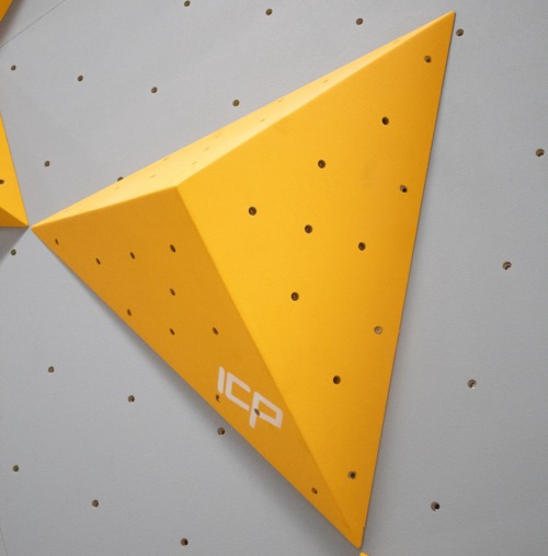Yellow ICP Kai K1.1 S climbing volume viewed front-on, mounted on a grey textured climbing wall.