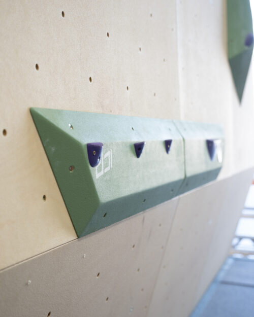 Medium green ICP Harry H2.6-7 M thin rail climbing volume on a wood-textured wall, fitted with small jib footholds for precision footwork.