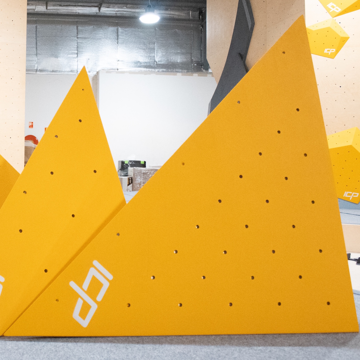 Yellow ICP Jade J2.1 L climbing volume stacked on safety matting, front view, ready for route setting on the wall.