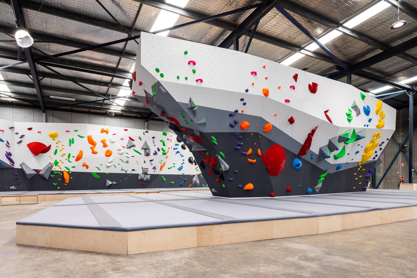 A sleek black, grey and white bouldering gym consisting of climbing walls and safety matting built by rock climbing wall builders ICP. 