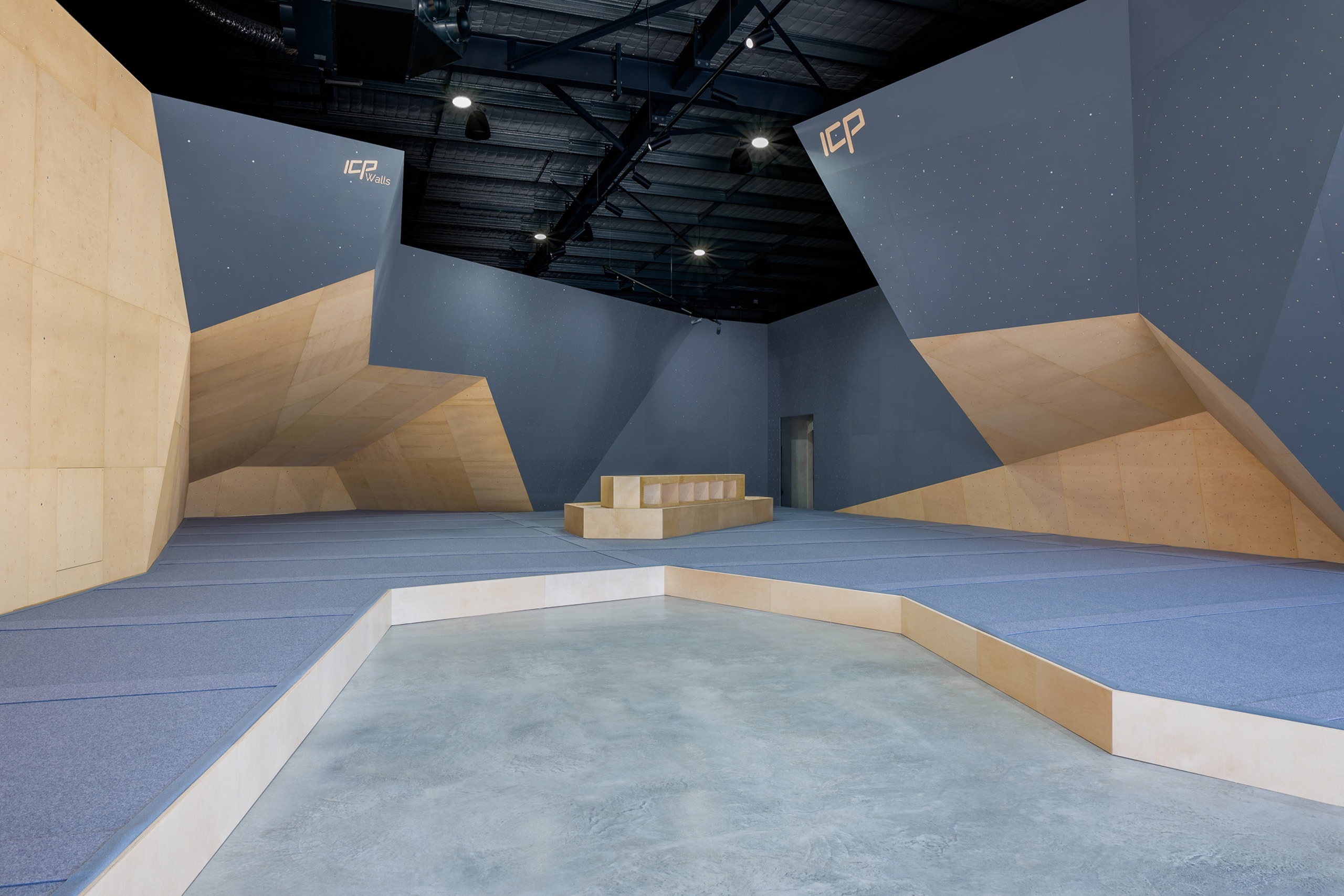 A sleek black, grey and white bouldering gym consisting of climbing walls and safety matting built by rock climbing wall builders ICP. 