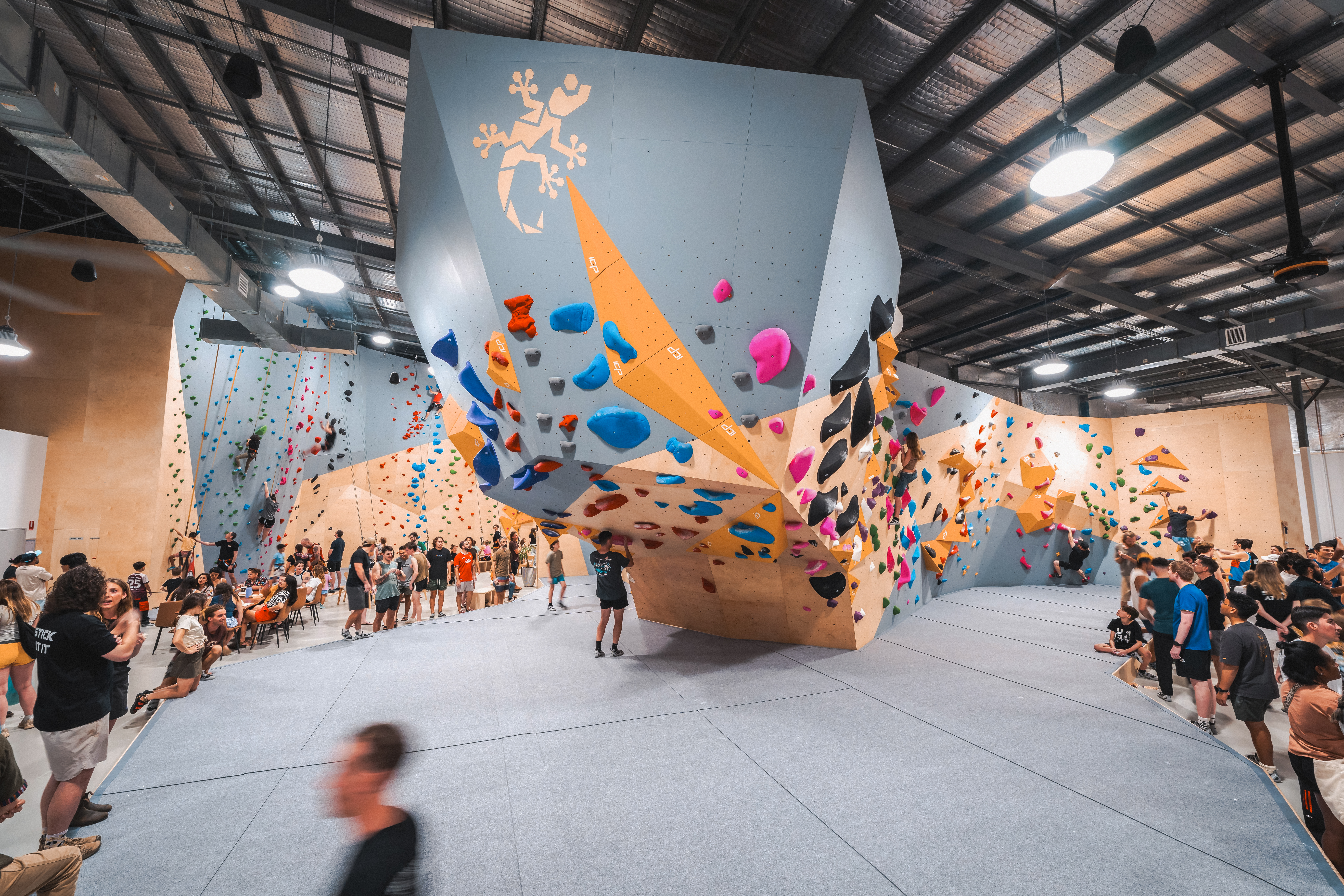 Gecko Climb – ICP Climbing Wall Builder | Bouldering and Rope Walls Gecko Climb facility with ICP-built grey and wood textured bouldering walls, yellow ICP Volumes, rope walls in the background, and grey safety mats.