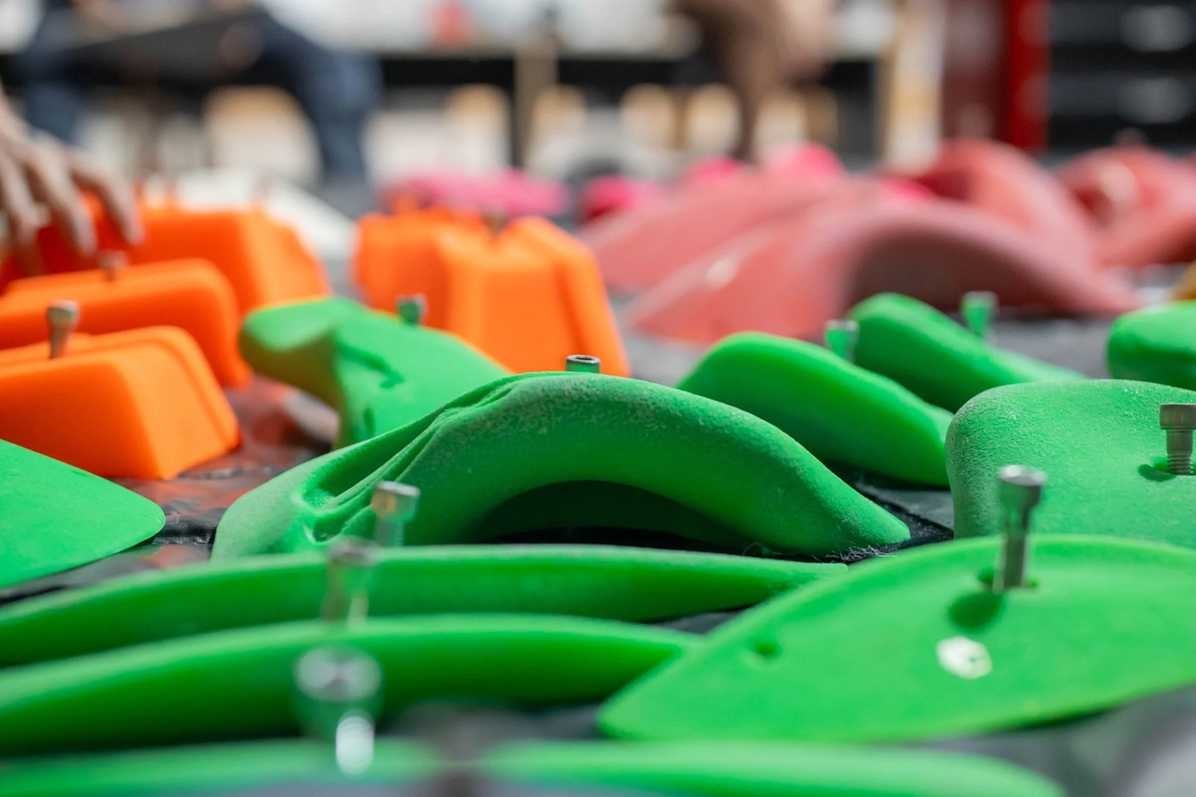 Close-up of colourful climbing holds and bolts prepared for routesetting in an indoor climbing gym.