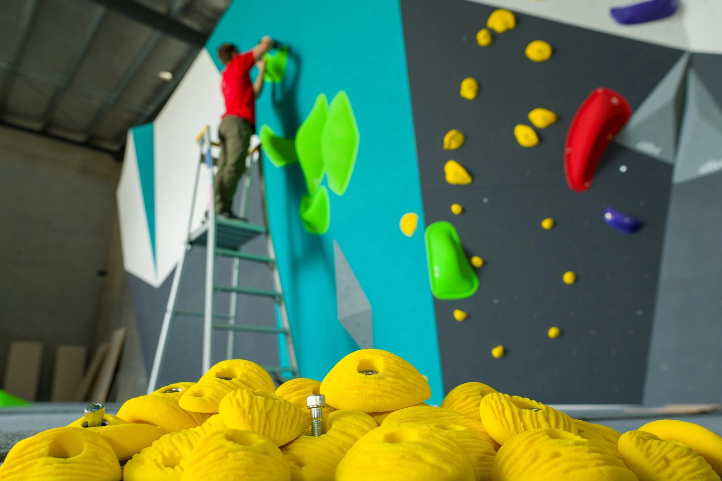 Route setter installing climbing holds on an ICP indoor climbing wall.