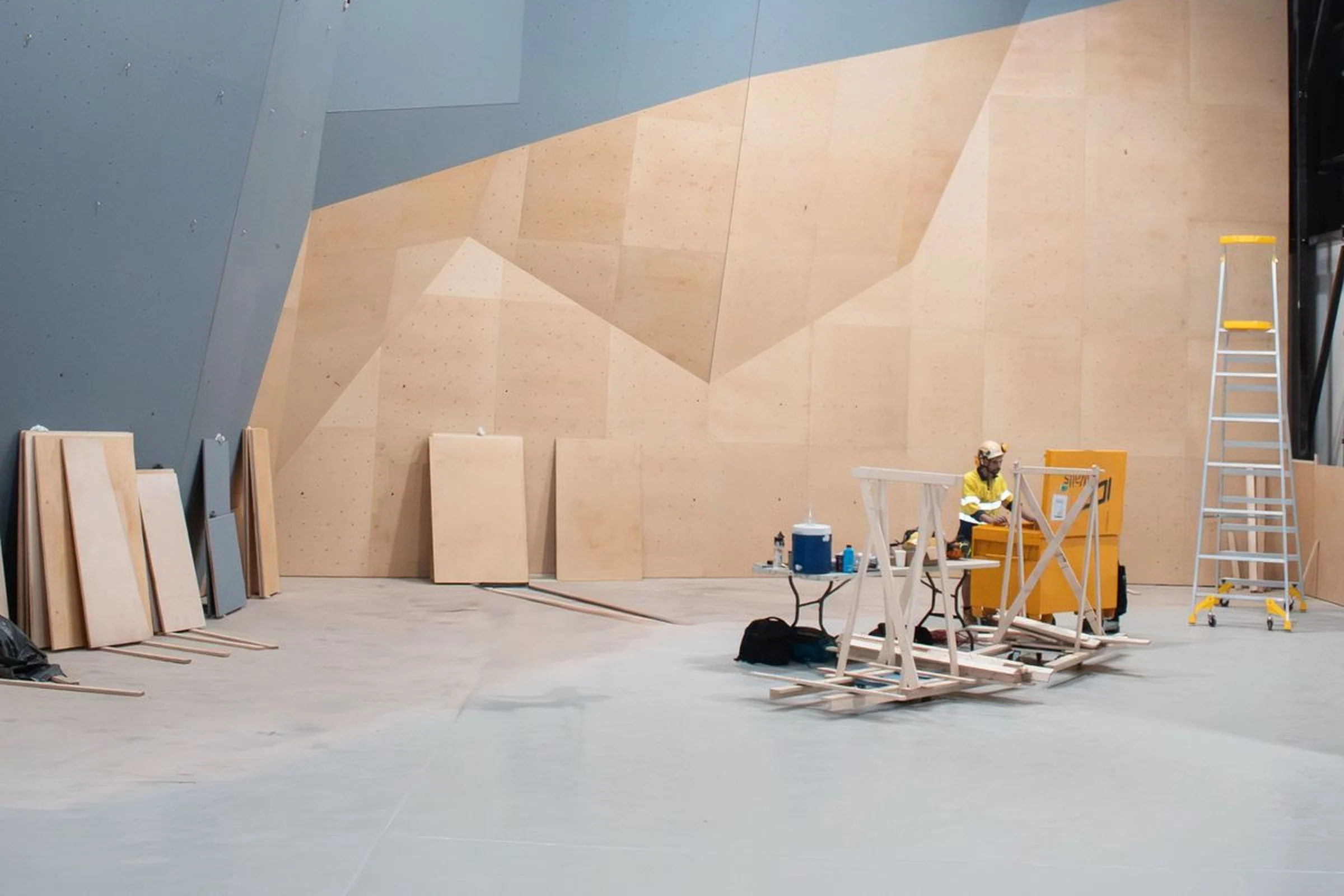 ICP builders working on the lower section of a modern indoor climbing wall installation inside a large facility.