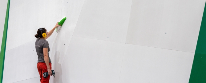 Routesetter planning the opening set for ICP-built bouldering gym. The wall is blank and holds are ready to go up.