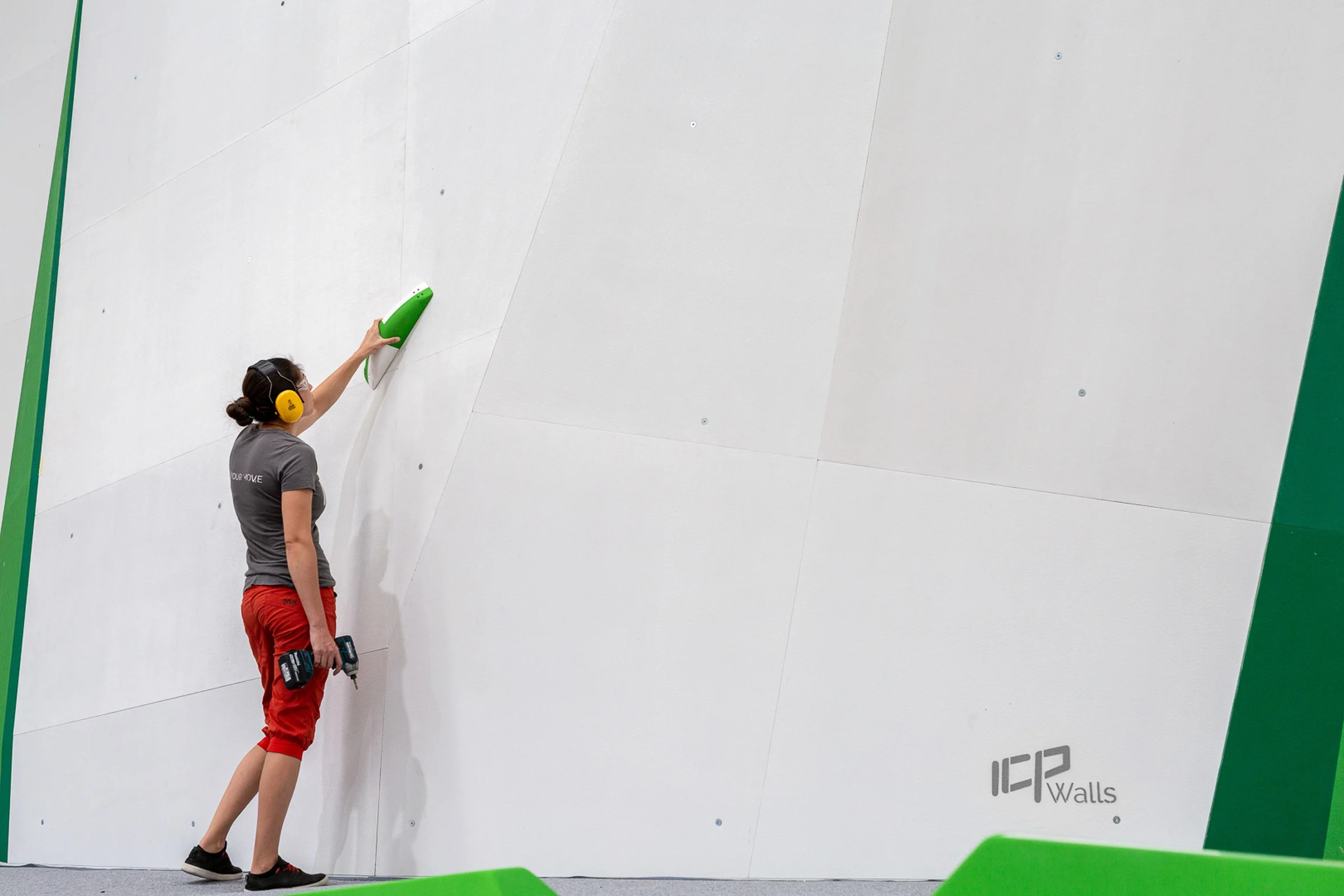 Routesetter planning the opening set for ICP-built bouldering gym. The wall is blank and holds are ready to go up.