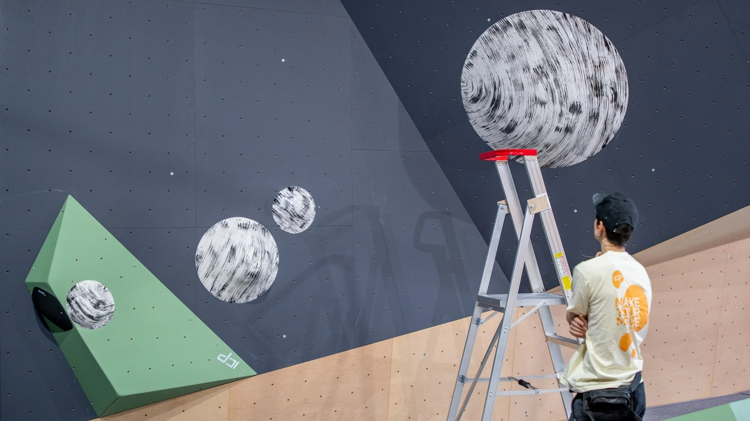 Routesetter ponders movement on the climbing wall with climbing volumes and aesthetic climbing holds at an ICP-built climbing gym.