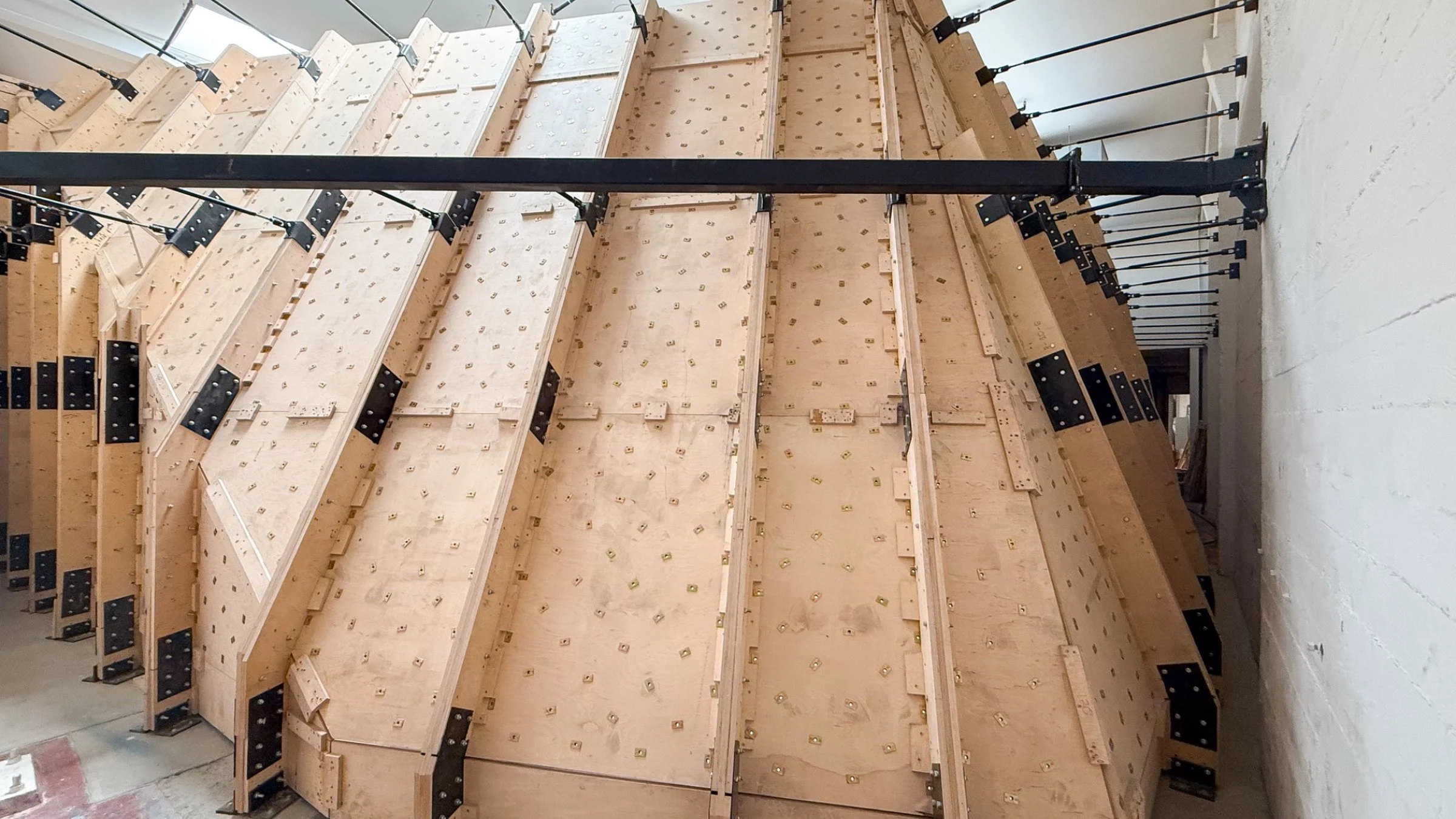 Rear view of the California Climbing Collective bouldering wall showing the engineered timber frame, structural supports, and mounting system during construction.